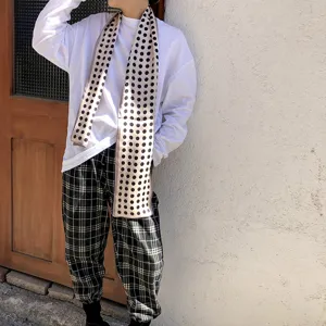 Dettaglio di un elegante foulard di seta a pois indossato da una modella in un contesto casual.