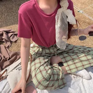 Tenue décontractée de printemps avec t-shirt rose, pantalon à carreaux et foulard.