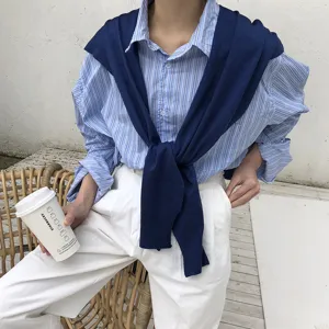 Vue détaillée d'une chemise à rayures bleues avec pull marine drapé sur les épaules.