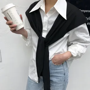 Vue détaillée de la chemise blanche associée à un pull écharpe d'épaule en tricot noir.