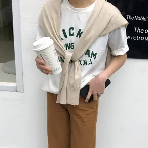 Vue détaillée de la tenue style coréen avec t-shirt blanc et châle en tricot beige.