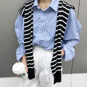 Vue détaillée d'une chemise rayée bleue décontractée avec pull en tricot noir et blanc.