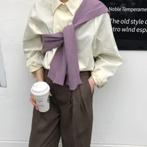 Detailed shot of stylish solid color knit shawl worn over shirt, perfect for casual office wear.