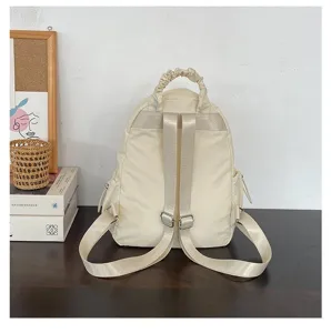 Gedetailleerd uitzicht von casual beige nylon rugzak op donkere houten tafel met woonaccessoires.
