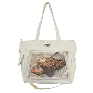 Vue détaillée du sac cabas en toile crème avec poche transparente, bandoulière pratique.