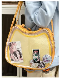 Close-up of cute cat shaped transparent ita bag with anime badges and cards display detail.