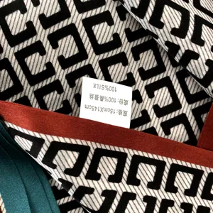 Gros plan detaille sur un foulard en soie avec motif geometrique et etiquette.