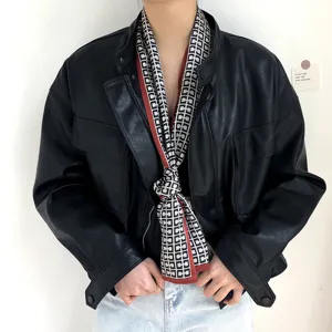Détail d'écharpe en soie avec motif géométrique noir et blanc élégant et bordure rouge.