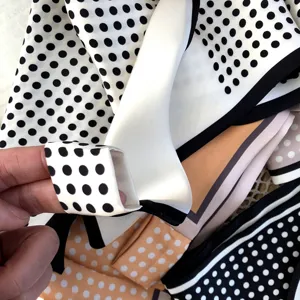 Gros plan détaillé d'un foulard en soie à pois stylé, montrant la texture lisse et les bords.