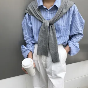 Vue détaillée d'une chemise rayée avec châle en tricot gris et pantalon blanc élégant.