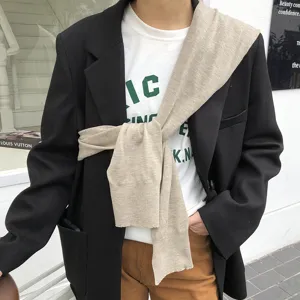 Gros plan détaillé d'un élégant châle écharpe en tricot drapé sur blazer noir et t-shirt.