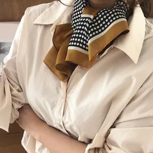 Detail shot of a silk neckerchief with polka dots and color-blocking design, elegant accessory.