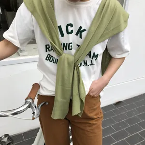 Tenue décontractée pour femme avec t-shirt blanc et élégant châle en tricot vert.
