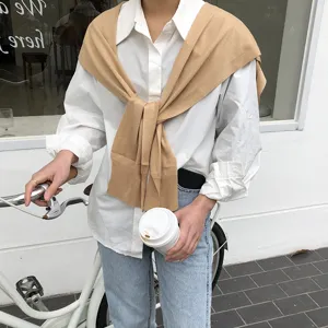 Cape en tricot tendance associée à une chemise blanche classique et un jean élégant.