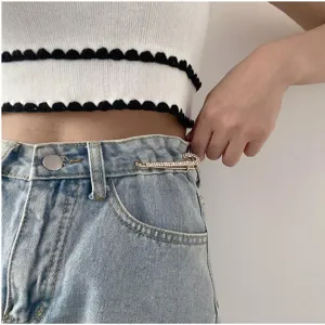 Rhinestone safety pin waist tightener detail shot, perfect for adjusting denim trousers or dresses.