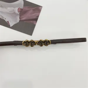 Primer plano de la hebilla de metal de cuatro rosas de bronce vintage y el cinturón fino.