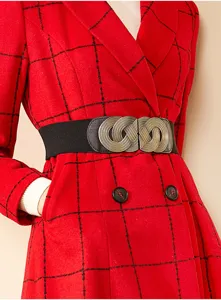 Primer plano del detalle de cinturón elástico ancho de mujer con hebilla de metal y abrigo rojo.