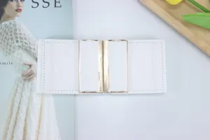 Detalle de cinturón elástico ancho blanco con cierre de metal y acabado texturizado.