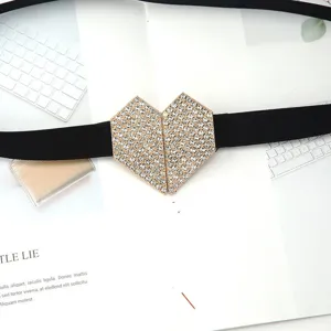 Primer plano detalle de hebilla de corazón con pedrería brillante en cinturón elástico negro.