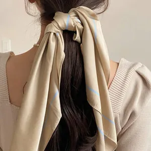Close-up detail of smooth satin hair scarf tied on long hair with elegant blue stripes.