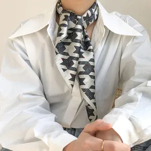 Close-up detail of a women's vintage geometric silk square scarf worn with white shirt.