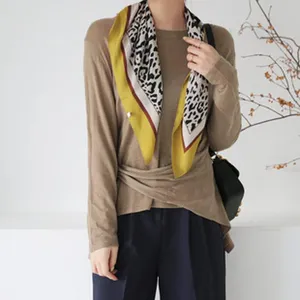 Detailed shot of a stylish leopard print square scarf worn on a model, spring fashion accessory.