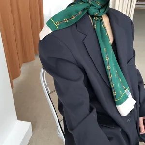 Écharpe longue en soie verte avec imprimé chaîne et mors, élégant accessoire ruban.