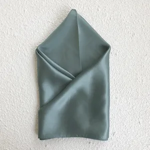 Detail shot of a elegant grey-green mulberry silk square scarf, soft and smooth texture.