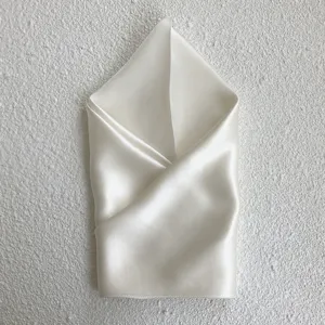 Detailed view of an elegant ivory silk square scarf, soft texture and refined natural sheen.