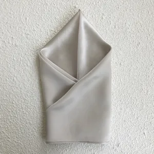 Detailed close-up shot of a luxurious light grey mulberry silk square scarf neatly folded.