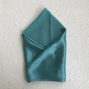 Detailed shot of the elegant teal silk scarf, showing smooth fabric texture and neat folding.