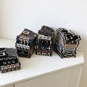 Nahaufnahme von mehreren elegant gefalteten, gemusterten Strickschals auf dem Tisch.