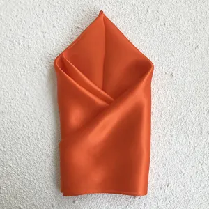 Detailed view of a premium orange silk square scarf neatly folded, elegant accessory for autumn.