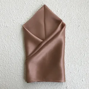 Close-up detail of smooth brown silk square scarf showcasing fine fabric texture and soft drape.