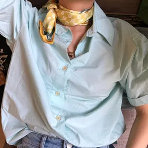 Joli détail de chemise à manches courtes bleu clair avec un beau foulard en soie jaune.