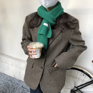 Detailaufnahme eines gemütlichen grünen Strickschals, getragen mit Blazer und Kaffeetasse.