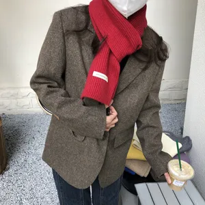 Detailansicht eines kuscheligen roten Strickschals mit kleinem Etikett, kombiniert mit Sakko.
