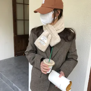 Detailed shot of fluffy plush winter scarf worn with brown blazer and coffee cup outdoors.