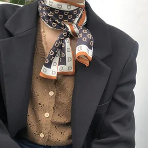 Gros plan détaillé du foulard en soie pour femmes au motif imprimé de lettres élégantes.