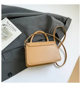 Close-up detail of a chic caramel structured top-handle shoulder bag styled on a grey blazer.