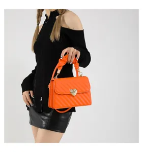 Orange mini crossbody bag detail showing heart metal lock and scrunchie handle design.
