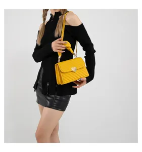 Detailed view of fashionable yellow quilted shoulder bag with heart clasp and elegant handle.