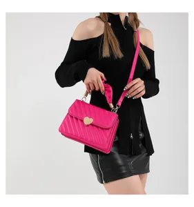 Stylish pink crossbody bag for women with quilted design and gold heart closure, perfect for daily.