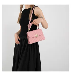 Close-up of pink quilted shoulder bag with chic heart clasp and cute ruffled handle detail.