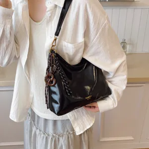 Black patent leather underarm shoulder bag with metal strap and chic charms detail.