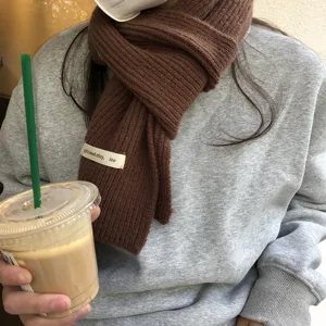 Nahaufnahme eines kuscheligen braunen Strickschals mit grauem Sweatshirt, Lifestyle-Look.