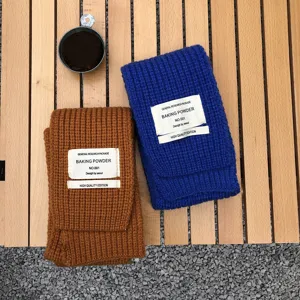 Detailaufnahme von gestrickten Winterschals mit dekorativen Stoffetiketten und Wolle.