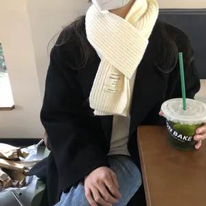 Nahaufnahme des gemütlichen weißen Strickschals für den Winter mit stilvollem gewebten Etikett.