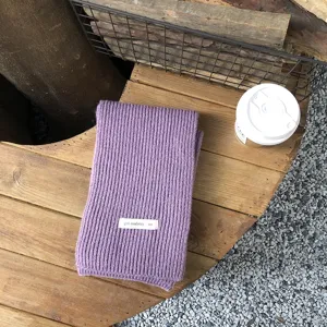 Nahaufnahme Detail des lila gerippten Strickschals, weiche Textur im gemütlichen Lifestyle.
