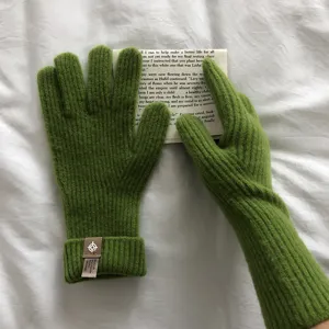 Detailaufnahme von kuscheligen grünen Strickhandschuhen mit weicher warmer Wolltextur.